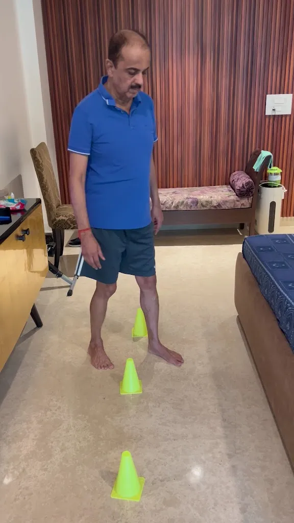 A patient practising a cone-walking balance and gait drill during a home rehabilitation session